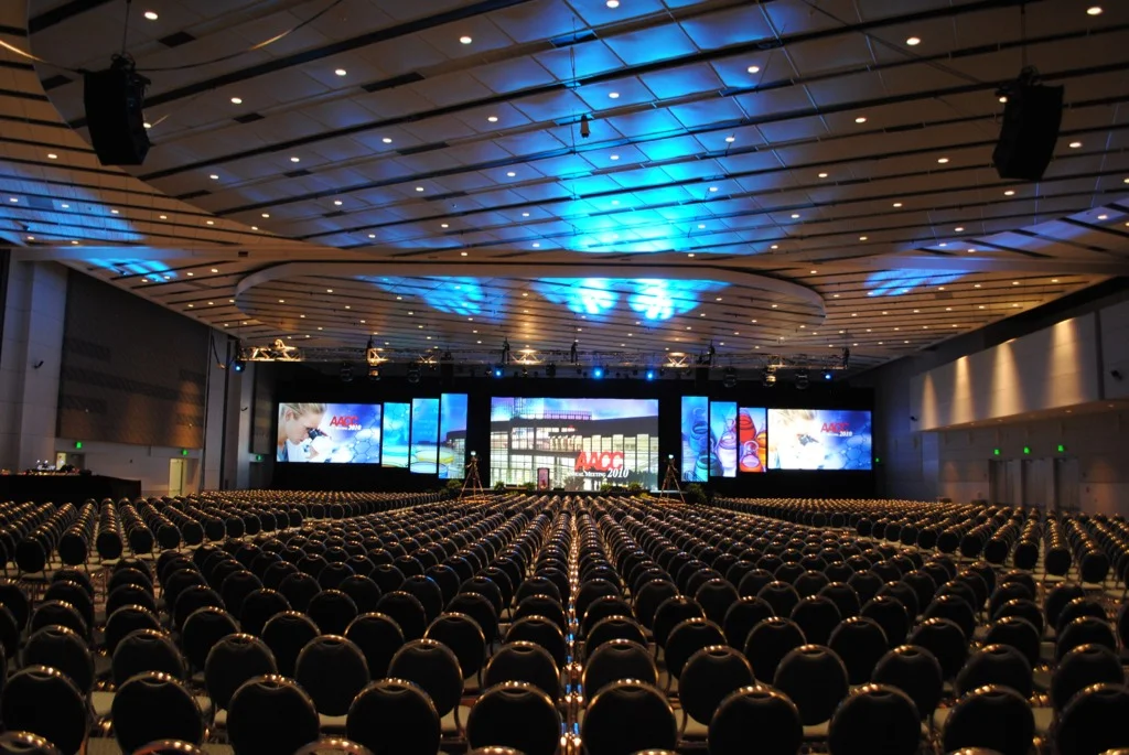 Conference auditorium with blue lighting and multiple stage screens