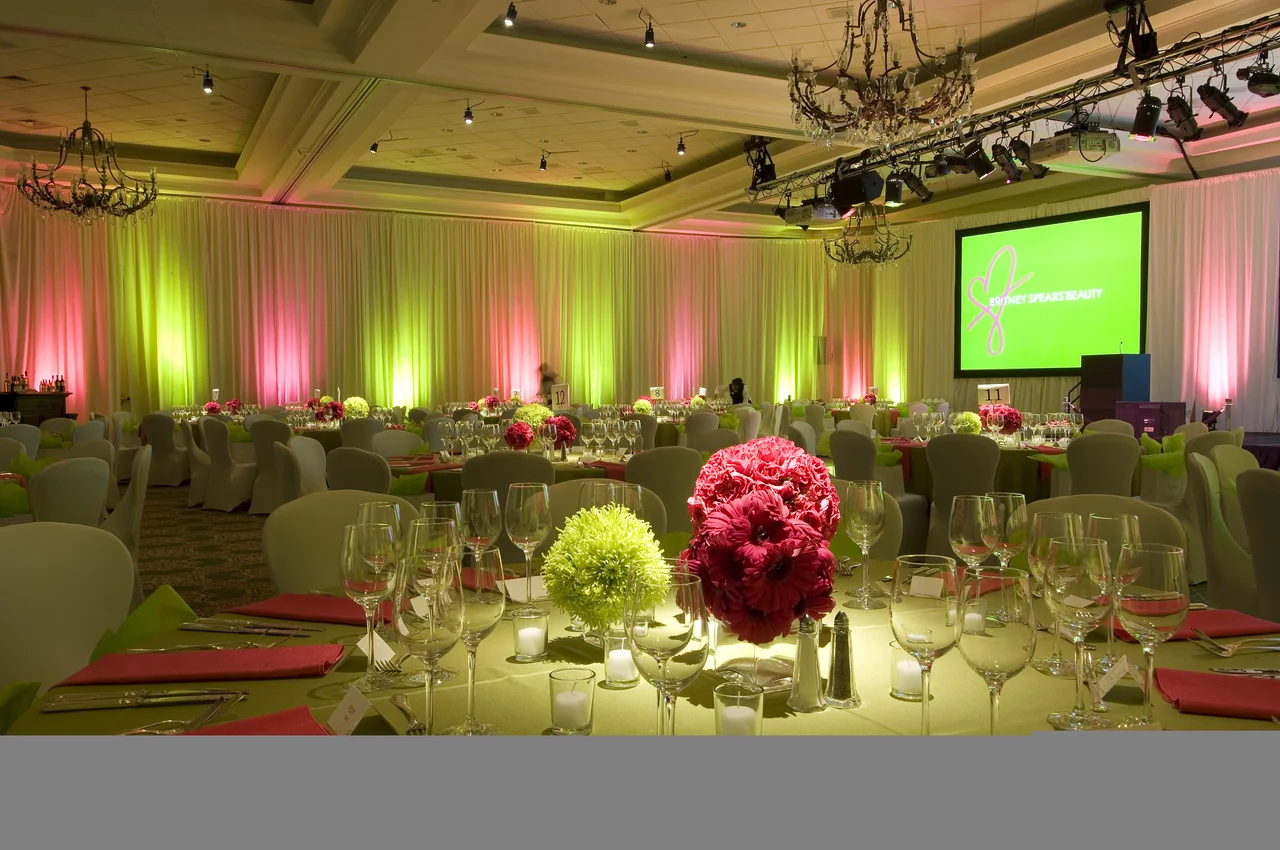 Banquet tables with pink and green uplighting and a presentation screen
