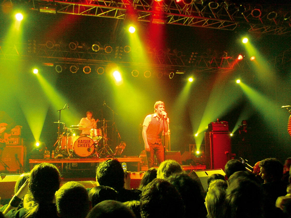 Singer and band performing under yellow and red lights
