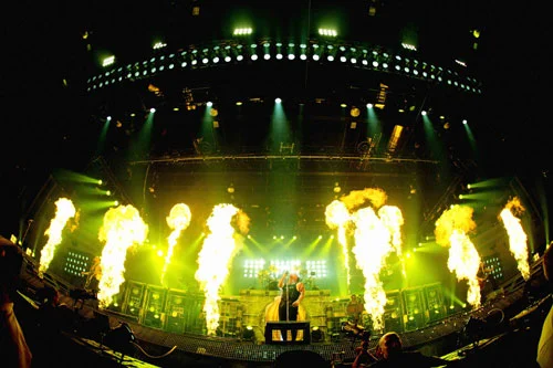 Concert stage with green lighting and flame effects