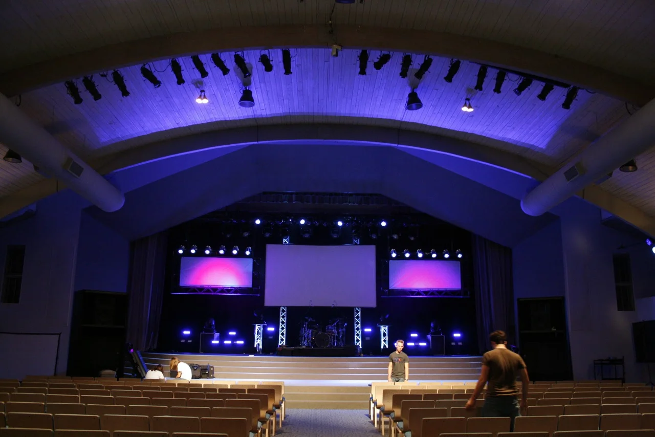 Auditorium stage with projection screens and blue architectural lighting