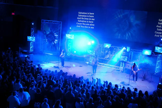 Live worship performance with blue lighting and stage screens