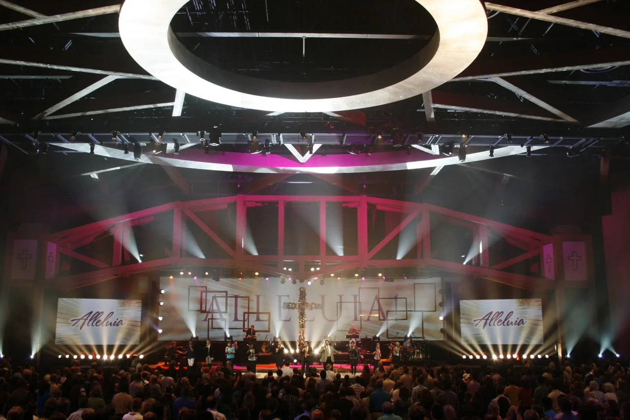 Church event with white light beams, screens and a full audience