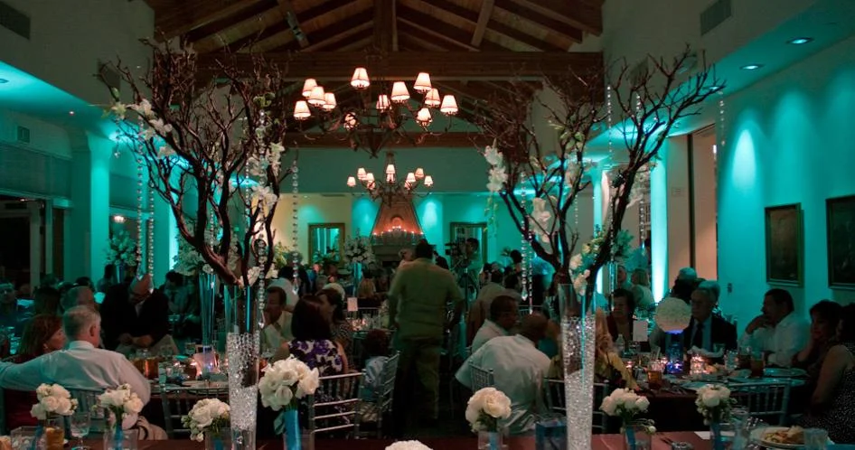 Reception with teal uplighting and tall floral centerpieces
