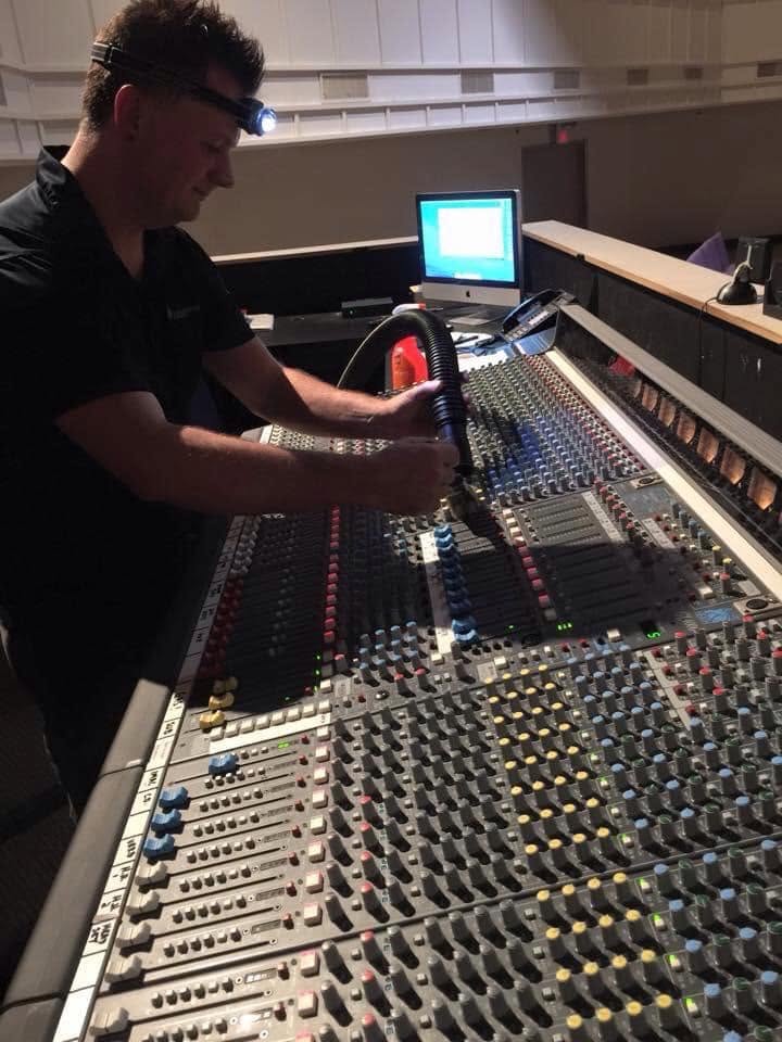 A technician working on an audio mixing console