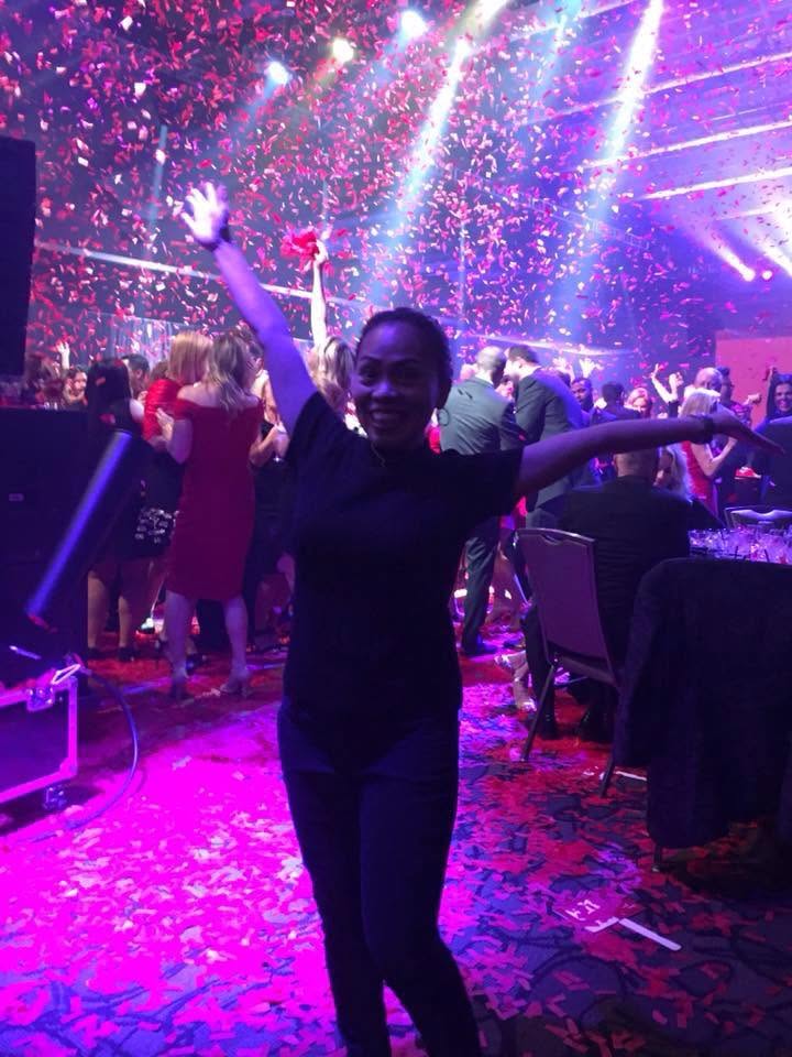 A guest celebrating beneath confetti and colorful event lighting